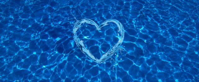Wasserstrahlen in Herzform im dunkelblauen Wasser